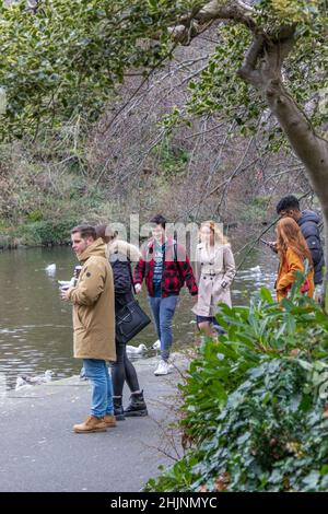 Menschen, die sich im Stadtpark um den kleinen See, St. Stephen’s Green City Park, Stadtfotografie, Straßenfotografie, Dublin, Irland ausruhen und spazieren gehen Stockfoto