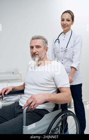 Lächelnde Physiotherapeutin und ihr männlicher Patient posiert vor der Kamera Stockfoto