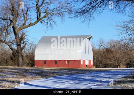 Eine rote Scheune mit Schnee und Himmel auf dem Land Stockfoto