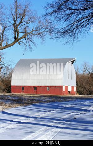 Eine rote Scheune mit Schnee und Himmel auf dem Land Stockfoto