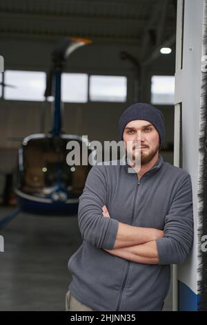 Bärtig, ernsthaft männlich, der im Hangar nach vorne blickt Stockfoto