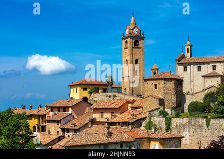 Glockenturm zwischen Steinhäusern unter blauem Himmel in der Altstadt von Monforte d'Alba im Piemont, Norditalien. Stockfoto