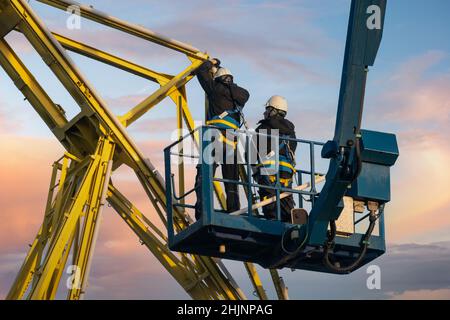 Montagearbeiter reparieren einen Hafenkran auf einem Hochhub Stockfoto