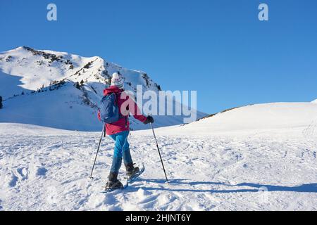 Nette ältere Frau Schneeschuhwandern im verschneiten l nette ältere Frau Schneeschuhwandern in der verschneiten Berglandschaft des Kleinwalsertal in Vorarlberg, Österreich Stockfoto