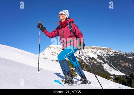Nette ältere Frau Schneeschuhwandern im verschneiten l nette ältere Frau Schneeschuhwandern in der verschneiten Berglandschaft des Kleinwalsertal in Vorarlberg, Österreich Stockfoto