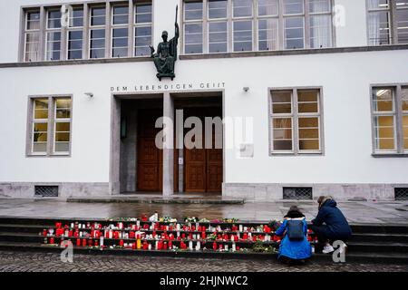 Heidelberg, Deutschland. 31st Januar 2022. Zwei Frauen zünden Kerzen vor dem Gebäude der Neuen Universität an. Eine Woche nach dem Rampage gedenkt die Universität Heidelberg mit einem Gedenkgottesdienst in der St. Peter-Kirche der Opfer. In Erinnerung an die getötete 23-jährige Studentin und ihre drei verletzten Kommilitonen werden alle Menschen aufgefordert, um 12:24 Uhr eine Minute Pause einzulegen. Quelle: Uwe Anspach/dpa/Alamy Live News Stockfoto