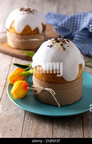 Traditioneller Osterkuchen, bunte Eier und Tulpen auf Holztisch. Stockfoto