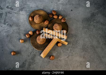 Schokoladentrüffel-Bonbons mit Zimt und Haselnüssen auf dunklem Hintergrund. Draufsicht Stockfoto