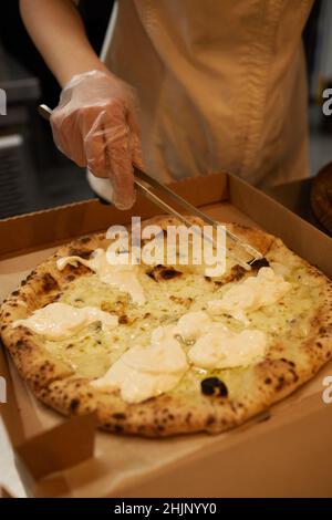 Pizza Margherita auf Marmorplatten vorbereiten.Pizzaiolo legt Pizzateig auf die Schale Stockfoto