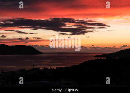 Wolkiger und außergewöhnlicher Sonnenuntergang in roten und orangen Farben an der Mittelmeerküste Stockfoto