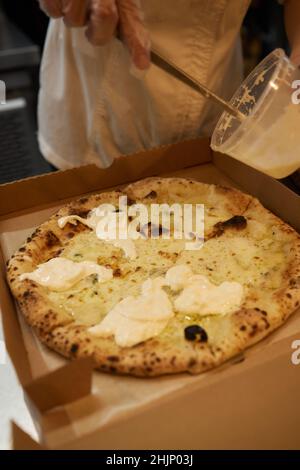 Pizza Margherita auf Marmorplatten vorbereiten.Pizzaiolo legt Pizzateig auf die Schale Stockfoto