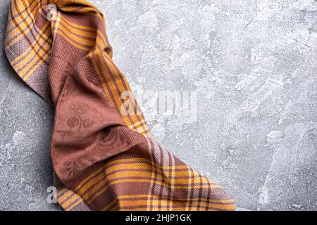 Draufsicht auf braunes gefaltetes Küchentuch oder Serviette auf grauem Beton-Hintergrund Stockfoto