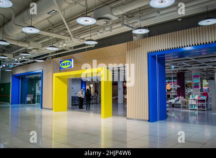 Moskau, Russland, September 2019: Eintritt in den IKEA-Store. Die Wache spricht mit einer schwarz gekleideten Frau. Im Inneren können Sie Waren, Bettwäsche, Karren sehen. Stockfoto