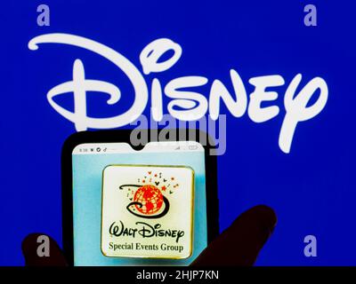 In dieser Abbildung wird das Logo der Walt Disney Special Events Group auf einem Smartphone-Bildschirm mit dem Disney-Logo im Hintergrund angezeigt. Stockfoto