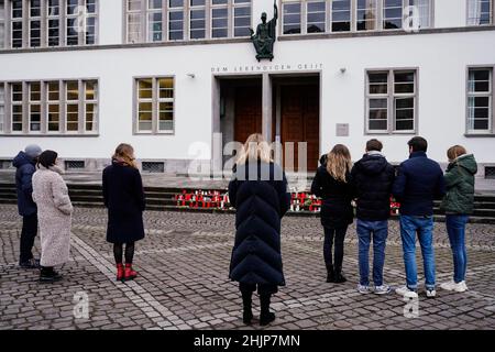 Heidelberg, Deutschland. 31st Januar 2022. Vor dem Haupteingang der Neuen Universität stehen Menschen für eine Schweigeminute. Eine Woche nach dem Rampage erinnert die Universität Heidelberg mit einem Gedenkgottesdienst in der St. Peter-Kirche an die Opfer. In Erinnerung an die getötete 23-jährige Studentin und ihre drei verletzten Kommilitonen werden alle Menschen aufgefordert, um 12:24 Uhr eine Minute Pause einzulegen. Quelle: Uwe Anspach/dpa/Alamy Live News Stockfoto