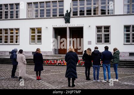 Heidelberg, Deutschland. 31st Januar 2022. Vor dem Haupteingang der Neuen Universität stehen Menschen für eine Schweigeminute. Eine Woche nach dem Rampage erinnert die Universität Heidelberg mit einem Gedenkgottesdienst in der St. Peter-Kirche an die Opfer. In Erinnerung an die getötete 23-jährige Studentin und ihre drei verletzten Kommilitonen werden alle Menschen aufgefordert, um 12:24 Uhr eine Minute Pause einzulegen. Quelle: Uwe Anspach/dpa/Alamy Live News Stockfoto