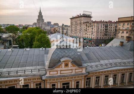 Moskau, Russland. Eines der stalinistischen Hochhaus-Gebäude links. „Wolkenkratzer“ auf dem Gartenring. Sowjetisches Wohnhaus rechts und Dach im Vordergrund. Stockfoto