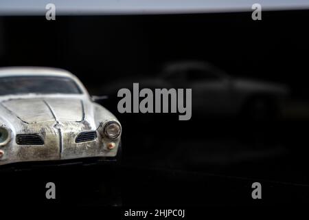 Ein Modell eines alten klassischen schäbigen Autos auf glänzendem schwarzem Glas. Nahaufnahme. Stockfoto