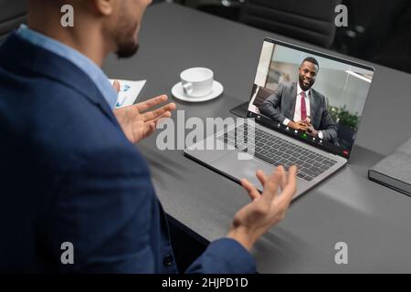 Von einem Geschäftsmann, der eine Videokonferenz mit einem schwarzen Mann hatte, geschnitten Stockfoto