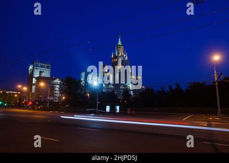 Das Hochhaus am Kotelnicheskaya-Ufer des Moskwa-Flusses. Stalinistischer Wolkenkratzer mit den Lichtern der Stadt am tiefblauen Himmel am Abend oder Stockfoto