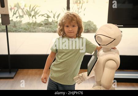 Kind und Roboter-Assistent mit Informationsbildschirm in Schutzmaske. Roboter Pandemie Zukunft. Roboter bieten Unterstützung für Kind. Humanoide Technologie. A Stockfoto