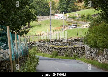 Autos und Lieferwagen hielten in der Ferne entlang der Trockensteinmauer, die b5343 lokale kleine schmale Straße säumte, die durch langdale Valley, Lake District, cumbria, Stockfoto