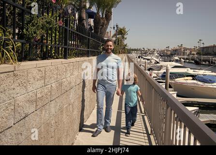 Gemeinsam spazieren gehen. Vater und Sohn gehen mit Händen auf die Promenade. Mann und Kind genießen gemächlichen Spaziergang Stockfoto