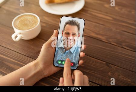 Virtuelles Meeting. Nicht erkennbare Dame, die einen Videoanruf mit ihrem Mann auf dem Handy hat, während sie im Café sitzt, kreative Collage Stockfoto