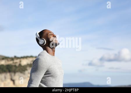 Seitenansicht Porträt eines glücklichen Mannes, der im Gebirge im Freien Musik hört und atmet Stockfoto