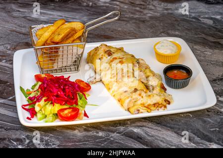 Hühnchen- und Pilzpfannkuchen oder Crepes mit Salat und pommes auf einem weißen Teller Stockfoto