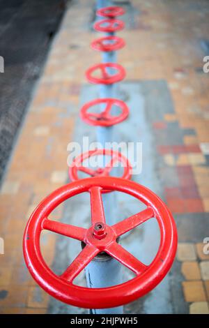 Reihe von alten Retro-Ventilräder rot selektiven Fokus mit Verlängerung Gerät über Out-of-Focus Hintergrund gefliesten Boden und perforierte Metallblech lackiert Stockfoto