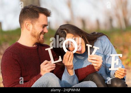 Junges Paar spielt mit einigen großen Liebe weißen Buchstaben Stockfoto