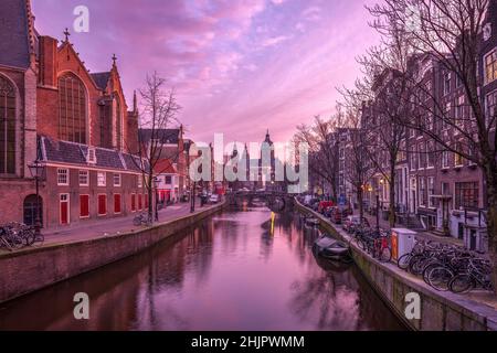 St. Nicolas Kirche und Brücke mit Blick auf einen Amsterdamer Kanal bei Sonnenaufgang mit Kanalbooten und Fahrrädern Amsterdam Holland Stockfoto