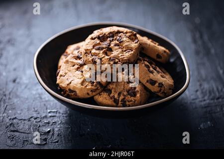 Schokoladenkekse mit Haselnuss und Schokoladenbröseln mit einem Glas Milch und Gläsern in Szene gesetzt Stockfoto