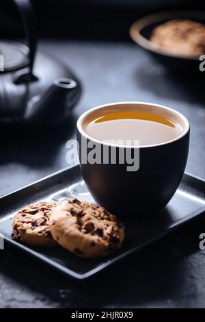 Tee- und Schokoladenkekse auf verschiedenen Hintergründen und in verschiedenen Tassen Stockfoto