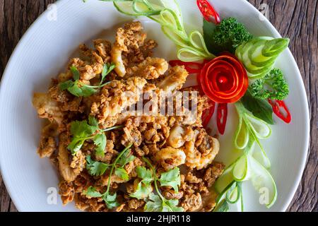 Gebratener Tintenfisch mit Knoblauch, knuspriger Teig, asiatisches Street Food auf einem Holzboden. Stockfoto