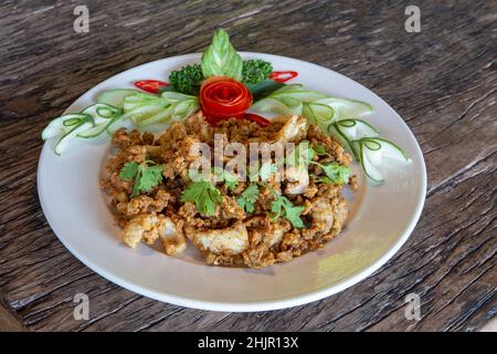 Gebratener Tintenfisch mit Knoblauch, knuspriger Teig, asiatisches Street Food auf einem Holzboden. Stockfoto