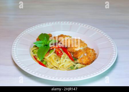 Spaghetti Green Curry mit knusprigem Huhn, Spaghetti mit grünem Curry-Huhn auf Holztisch Stockfoto