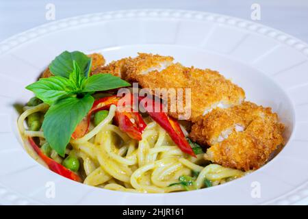 Spaghetti Green Curry mit knusprigem Huhn, Spaghetti mit grünem Curry-Huhn auf Holztisch Stockfoto