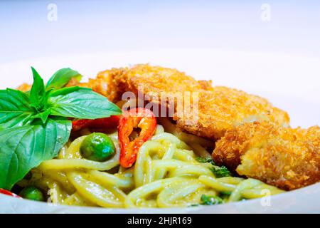 Spaghetti Green Curry mit knusprigem Huhn, Spaghetti mit grünem Curry-Huhn auf Holztisch Stockfoto