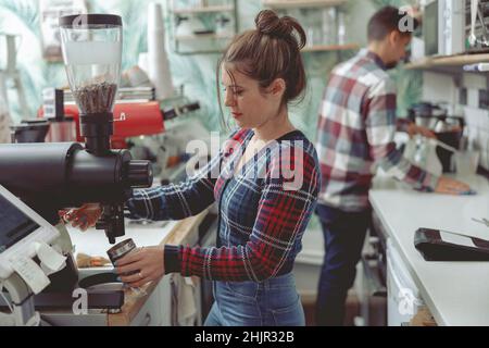 Porträt einer fokussierten Barista, die in der Nähe der Kaffeemühle im Café steht Stockfoto