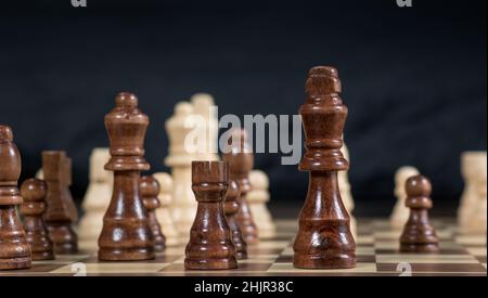 Schachbrett mit Schachspiel, das vor dunklem Hintergrund Black's Queen, Rook und King im Fokus gespielt wird Stockfoto