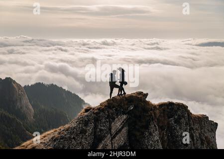 Junges Paar, das den Blick über die Wolken auf dem Berg genießt Stockfoto