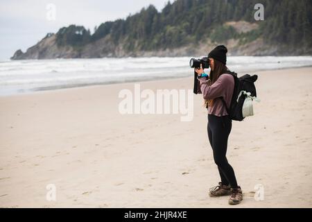 Junge Frau, die allein am Strand von Oregon fotografiert Stockfoto