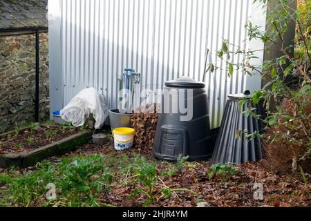 Schwarze Kompostbehälter zum Recycling von Lebensmitteln wurden in einem herbstlichen Wintergarten an einer gewellten Stallwand in Carmarthenshire Wales UK KATHY DEWITT vergast Stockfoto