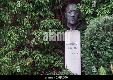 Grab von Heinrich Mann auf dem Berliner Dorotheenstädter Friedhof. Skulptur eines Schriftstellers auf einem Sockel, umgeben von Ästen Stockfoto