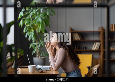 Gelangweilte, unzufrieden arbeitende Geschäftsfrau sitzt am Schreibtisch, während der Laptop müde über die Problemlösung nachdenkt Stockfoto
