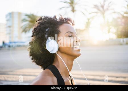 Schwarze Frau mit afro Haaren tanzt Musik am Strand zu hören Stockfoto