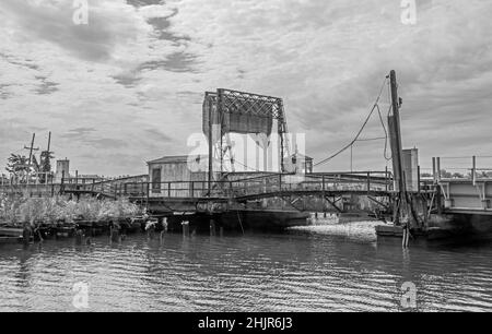 Eine alte Bascule-Eisenbahnbrücke (auch als Zugbrücke oder Hebebrücke bezeichnet) an einem grauen Tag mit einem Gegengewicht. In schwarz und weiß.
