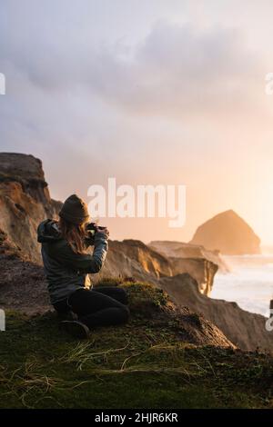 Fotografin, die den Sonnenuntergang an der Küste von Oregon fotografiert Stockfoto